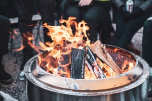 Group of people wearing coats and gloves gathered around fire pit